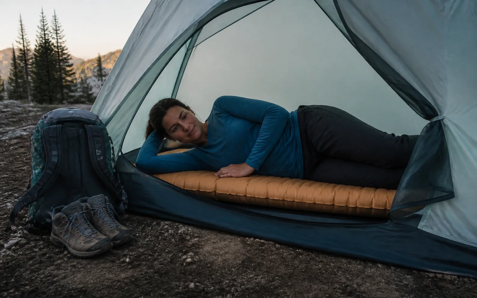 A side sleeper settling onto an insulated pad inside a small backpacking tent.